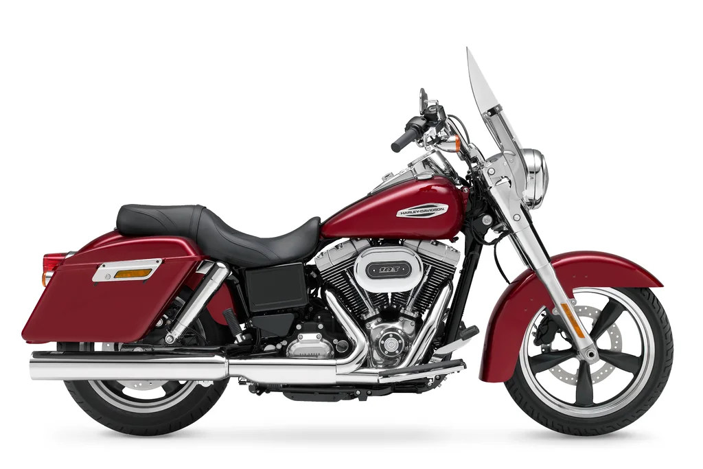 Vue studio côté droit d’une Harley-Davidson Switchback rouge, avec pare-brise, sacoches rigides et marchepieds pilote.