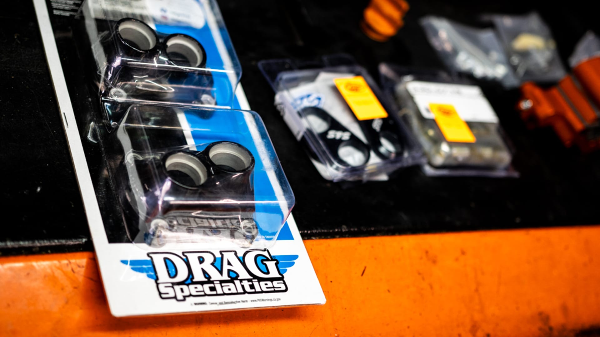 Blister Drag Specialties sur un établi d'atelier sombre — l'emballage bleu et blanc caractéristique